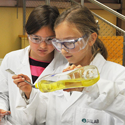 Junior - 2. bis 4. Schulstufe=2 Mädchen gießen Spülmittel auf einen Löffel